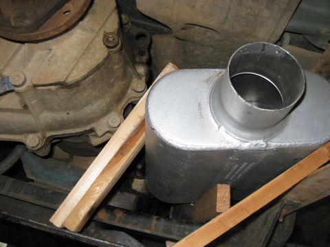 1995 Ford Bronco - A new muffler is being installed on a vehicle, supported by wooden blocks.