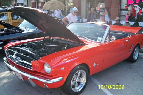 1985 Ford Bronco - A red 1965 Ford Mustang convertible is displayed with its hood open at an outdoor event.