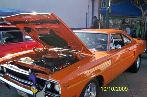 1985 Ford Bronco - An orange 1970 Plymouth Road Runner is displayed with its hood open at an outdoor event.