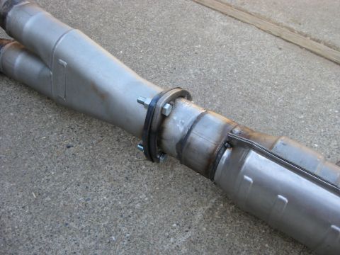 1995 Ford Bronco - Close-up of a custom exhaust y-pipe, showing welded joints and a bolted flange connection.