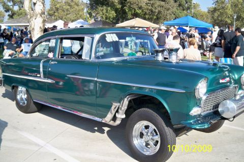 1985 Ford Bronco - A modified 1955 Chevrolet sedan, commonly known as a '55 Chevy, is displayed at an outdoor event.