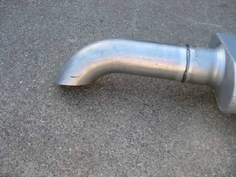 1995 Ford Bronco - Close-up of an exhaust pipe and muffler assembly on a concrete surface.