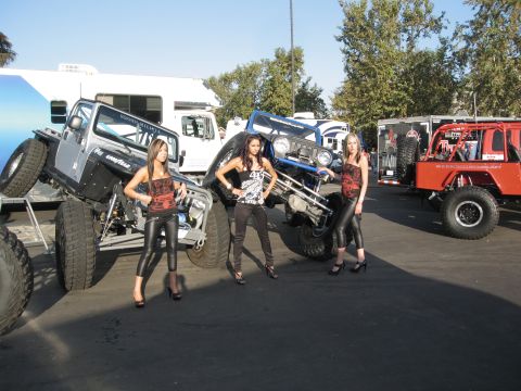 1986 Ford Bronco - Modified Jeep Wranglers are displayed with models at an outdoor event.