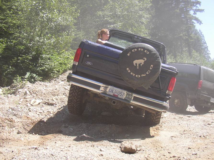 Ford Bronco on dirt trail, spare tire cover says Ford Bronco. License plate GNJ-057