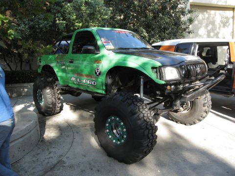 1986 Ford Bronco - Modified Toyota Tacoma pickup truck with extreme off-road modifications and large tires.