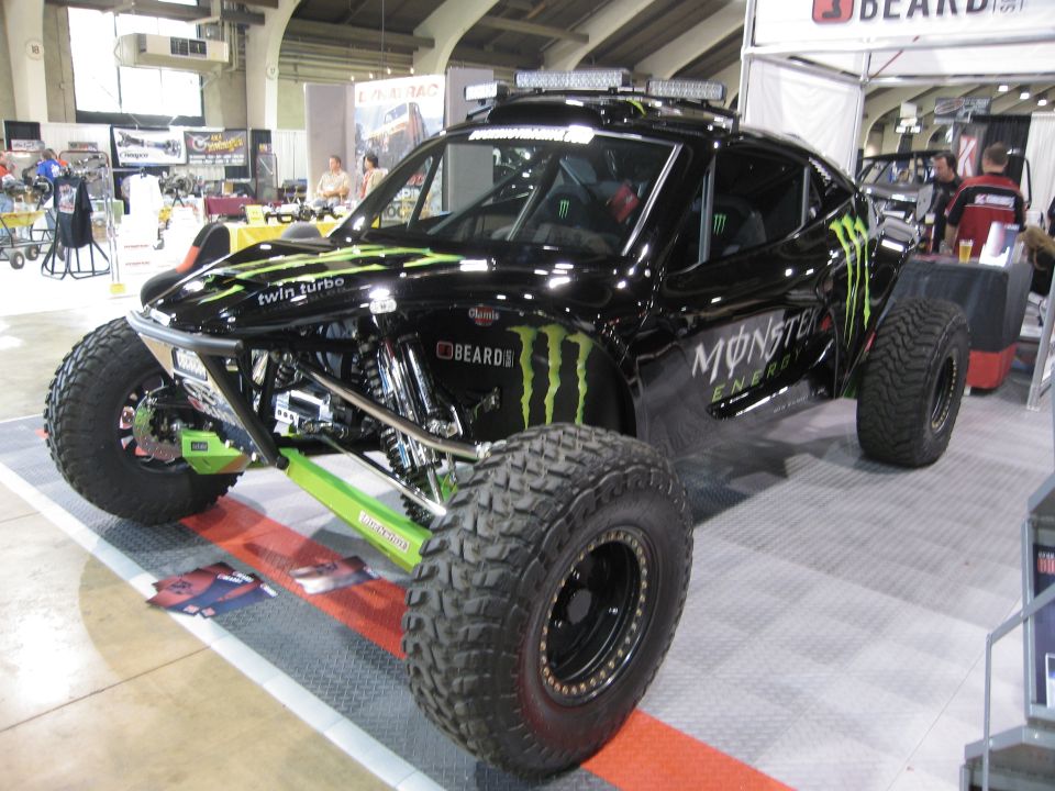 Black Monster Energy trophy truck with green accents and large off-road tires