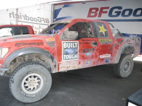 1986 Ford Bronco - Off-road racing truck with multiple sponsor decals, seen at an expo.