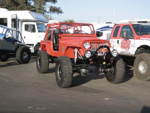1986 Ford Bronco - Several off-road vehicles are parked together on pavement under a clear sky.