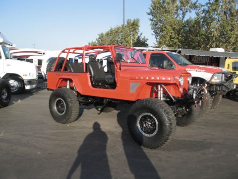 1986 Ford Bronco - Modified off-road Jeep with custom roll cage and oversized tires is displayed at an outdoor event.