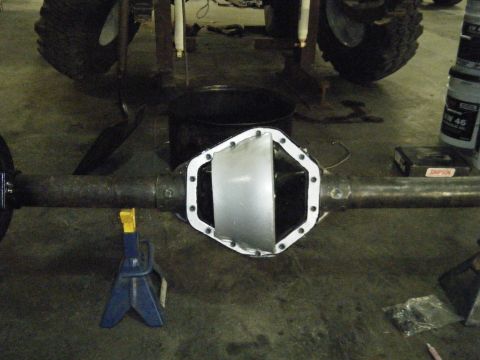 1978 Ford Bronco - A rear differential is shown with a new cover plate being installed, supported by jack stands.