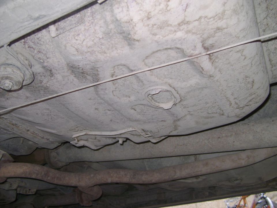 underside of car showing fuel tank and exhaust pipe, with SUPERMOTORS.NET watermark