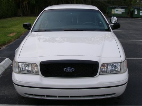 1999 Ford Crown Victoria - White Ford Crown Victoria police car front view, showing black grille and headlights.