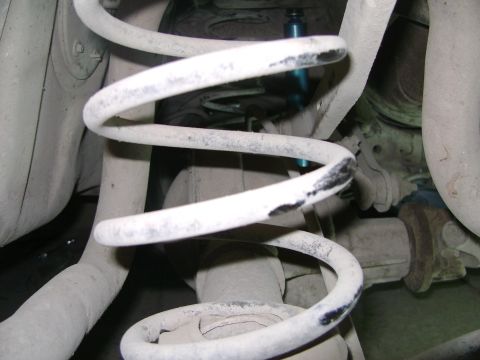 1998 Ford Crown Victoria - Close-up view of rear suspension components, including a coil spring and shock absorber, showing signs of wear and dust.