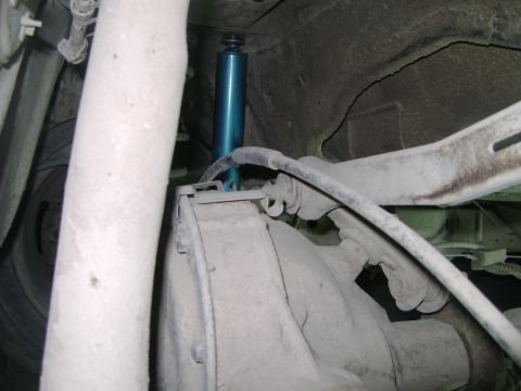 1998 Ford Crown Victoria - Close-up view of a blue shock absorber installed in the rear suspension system of a vehicle.