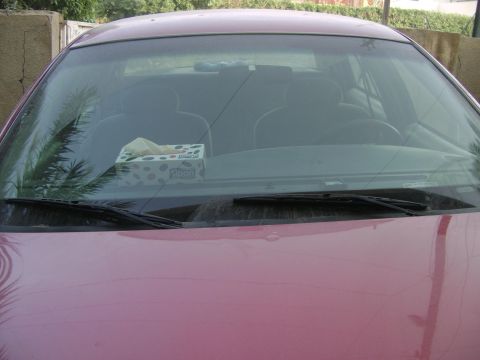 1998 Ford Crown Victoria - View of a pink car's interior, including the dashboard, seats, and windshield, with a box of tissues visible.
