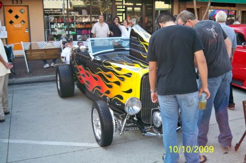 1985 Ford Bronco - A custom hot rod with flame decals is displayed outdoors, drawing attention from onlookers.
