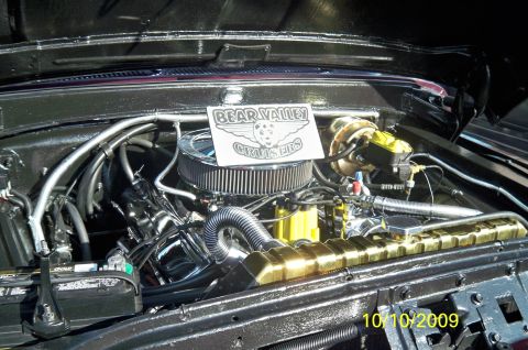 1985 Ford Bronco - The engine bay features a chrome air cleaner and a shiny gold radiator, with a club logo displayed.