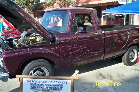 1985 Ford Bronco - A custom 1966 Ford F-250 pickup truck with flame decals is displayed with its hood open.