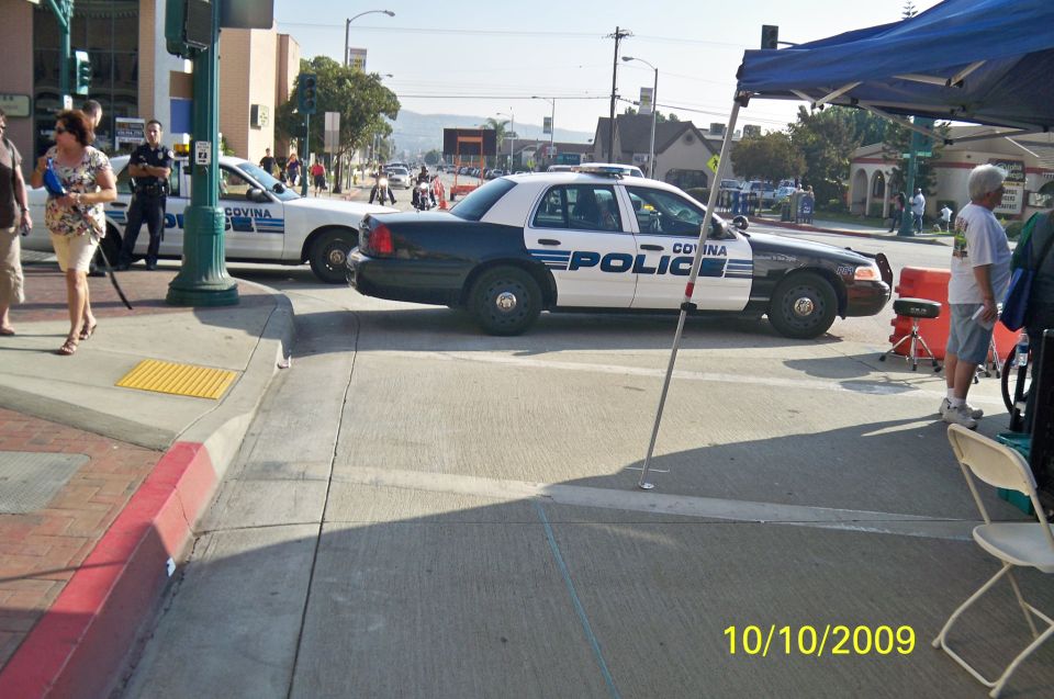 Side view of a black and white police car with "COVINA POLICE" text