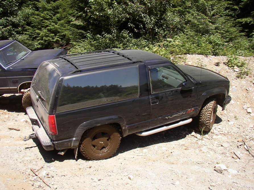Black 1995 GMC Yukon GT with muddy tires, parked next to another vehicle