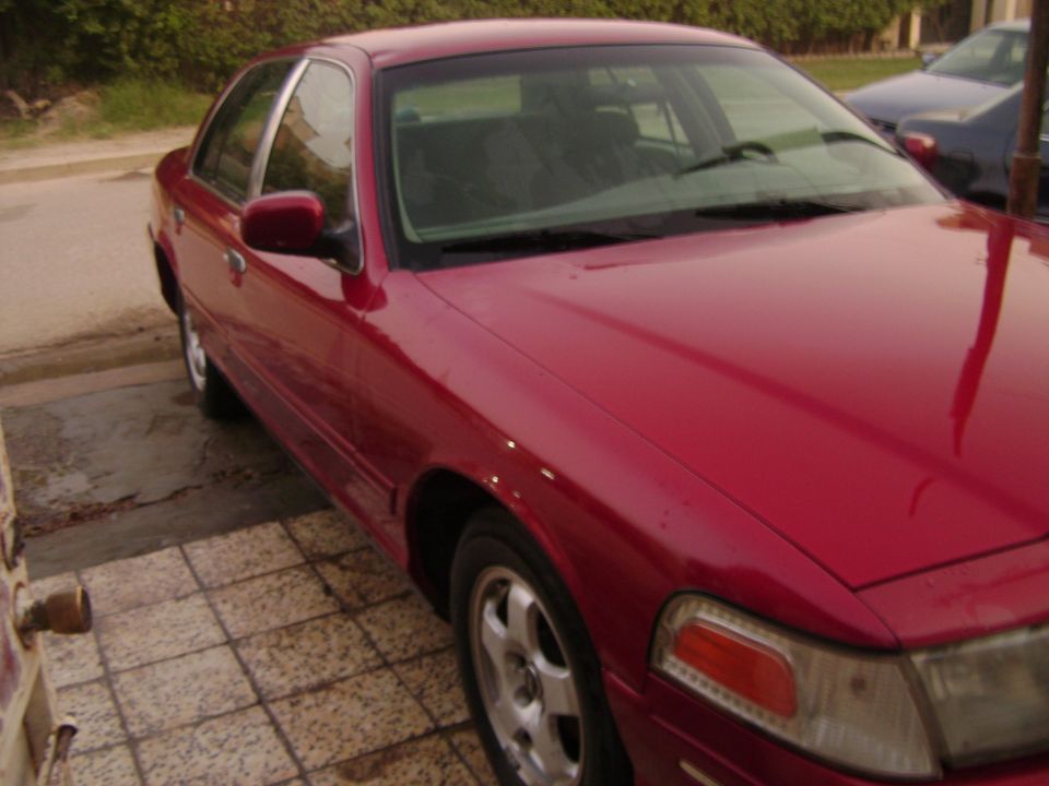 1998 Ford Crown Victoria, red, parked on a tiled driveway
