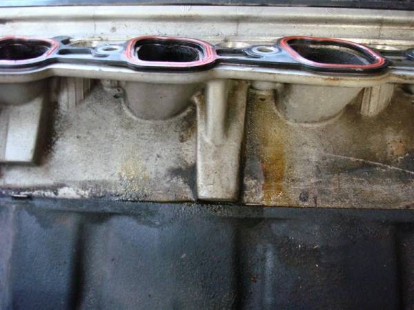 Engine intake manifold gasket with red sealant on aluminum housing