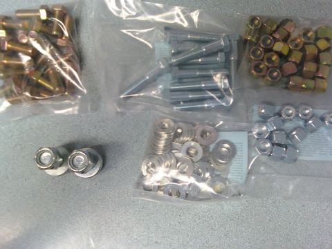 1984 Ford Bronco - Assorted hardware including nuts, bolts, and washers are displayed in plastic bags.