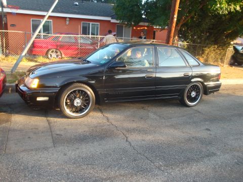 1993 Ford Taurus - A black 1993 Ford Taurus sedan is parked on a residential street.