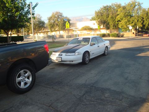 1993 Ford Taurus - White 1993 Ford Taurus with a black hood stripe is parked on a street.