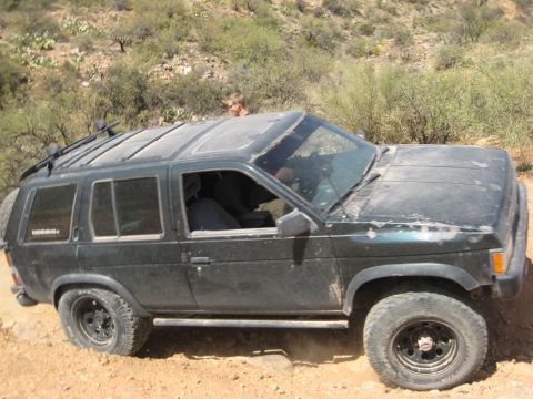 1996 Ford Bronco - This SUV is off-roading on a dusty, arid trail with sparse vegetation.