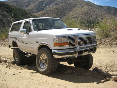 1996 Ford Bronco - This lifted Ford Bronco is navigating a rocky, off-road trail in a dry, mountainous area.