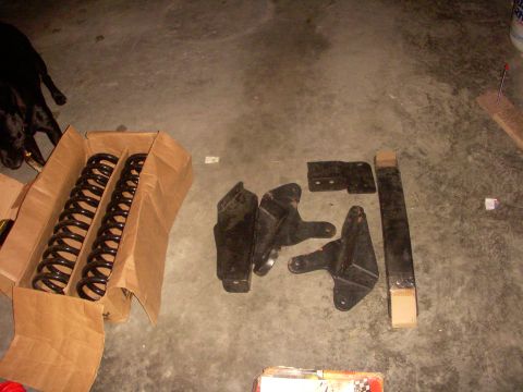 1993 Ford Bronco - Suspension parts are laid out on a concrete floor next to a box of coil springs and a dog.