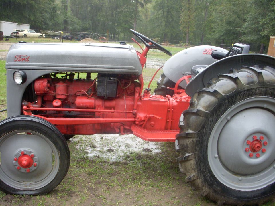 Gray and red Ford tractor, side view. Large rear tire