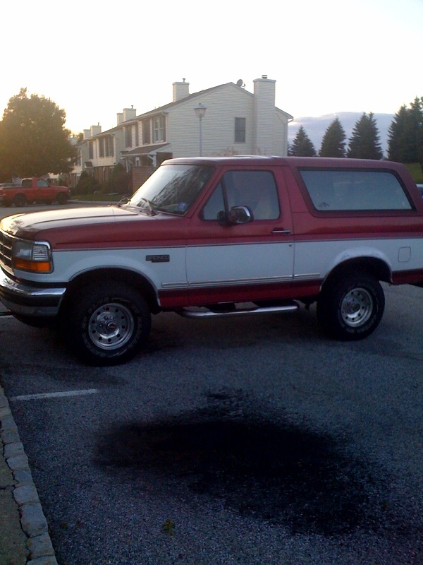 Red and white Ford Bronco SUV parked in a lot at dusk