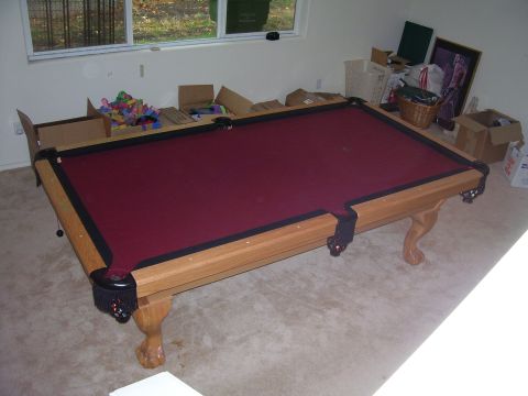 1991 Ford Bronco - A pool table sits in a room with boxes and a window, suggesting a storage or unfinished space.