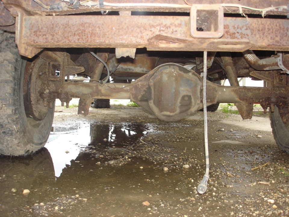 Rear axle assembly and suspension components of a heavily rusted vehicle, with a trailer hitch receiver visible above