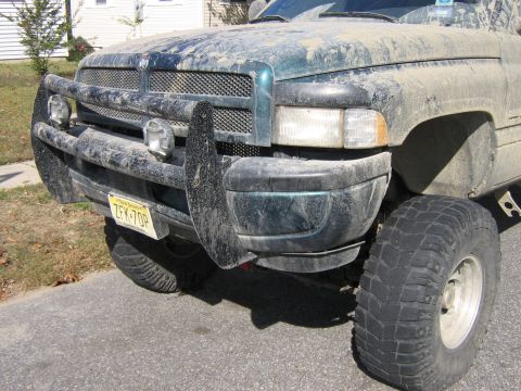 1998 Dodge 1500 - Front view of a mud-covered 1998 Dodge 1500 pickup truck with a heavy-duty brush guard.