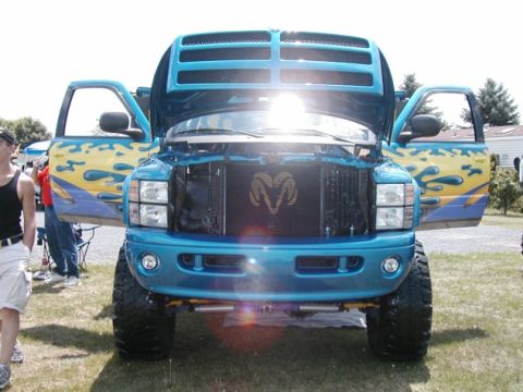 1994 Ford Bronco - Front view of a modified blue pickup truck with custom flame graphics and an open hood.