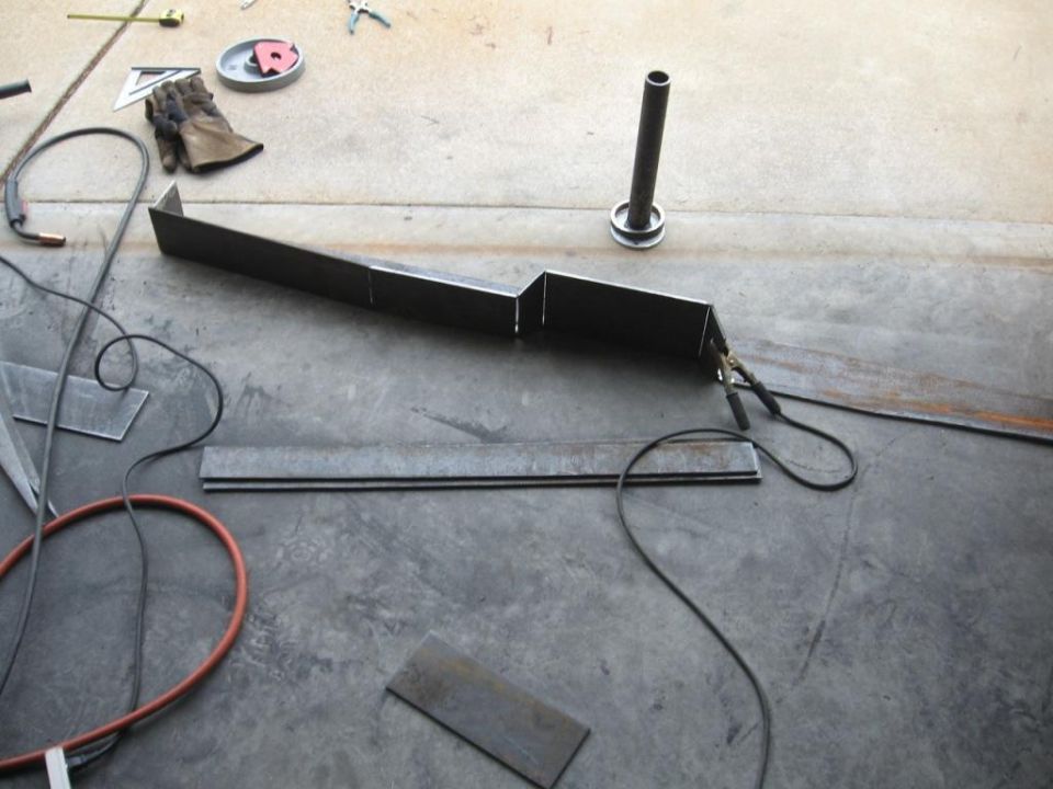 Metal bumper part on concrete floor with welding equipment and tools
