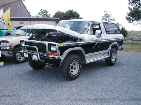 1994 Ford Bronco - This two-tone SUV, likely a 1978 Ford Bronco, has its hood raised, revealing the engine compartment. Another vehicle is partially visible t…