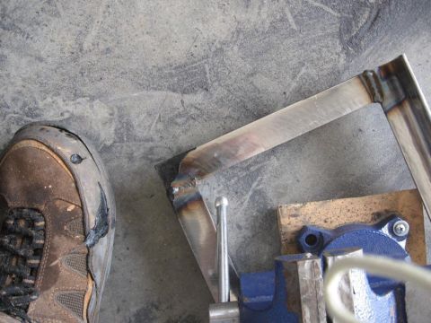 1995 Ford F-150 - Metal pieces being welded in a vise, with a work boot nearby. Supermotors.net logo is visible.