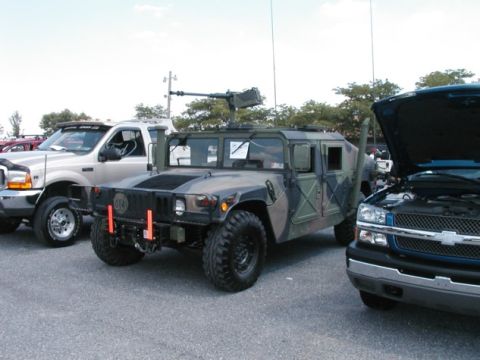 1994 Ford Bronco - A Humvee with a mounted machine gun is parked next to other vehicles.