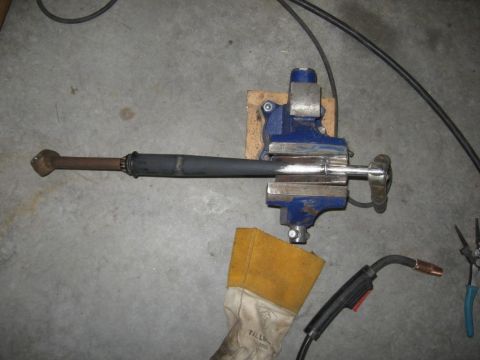 1995 Ford F-150 - A drive shaft is secured in a vise, ready for welding or modification. Welding gear and protective gloves are visible.