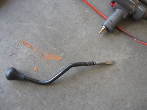 1995 Ford F-150 - A gear shifter lever with a black knob is shown on a concrete surface next to a pneumatic impact wrench.