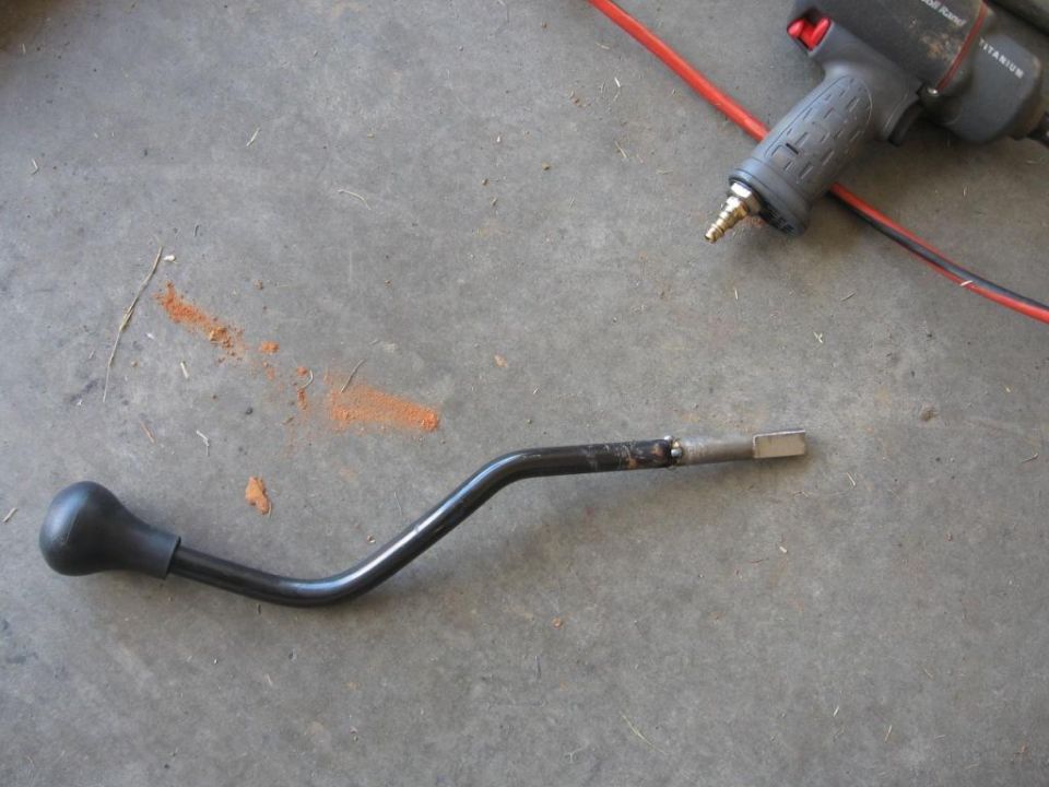 Gear shifter lever with black knob, next to an air impact wrench on concrete