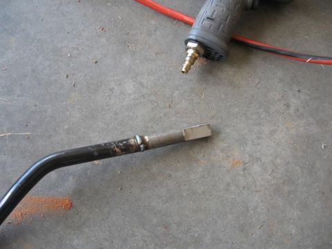 1995 Ford F-150 - A metal rod, possibly a shifter linkage, lies on a concrete surface next to an air tool.