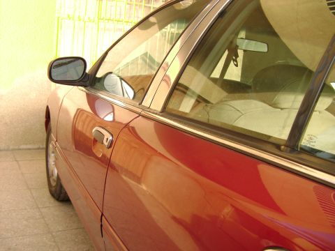 1998 Ford Crown Victoria - Side view of a red 1998 Ford Crown Victoria sedan with chrome trim.