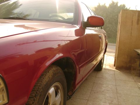 1998 Ford Crown Victoria - A red sedan is parked outdoors, with sunlight reflecting off its body panels.