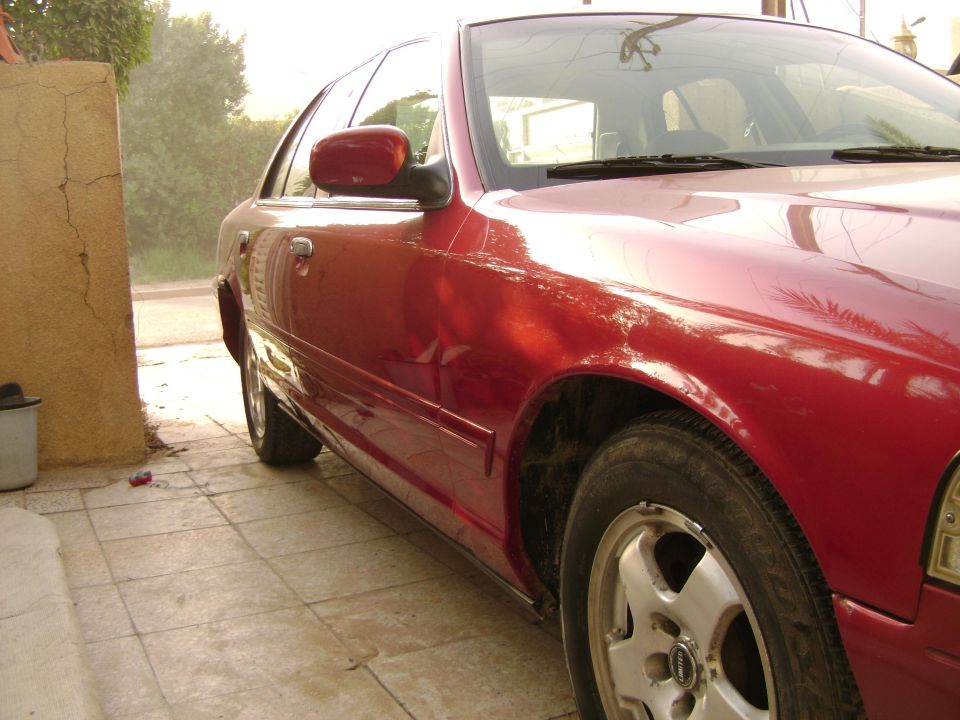 Red 1998 Ford Crown Victoria, front quarter view, parked on tiled ground