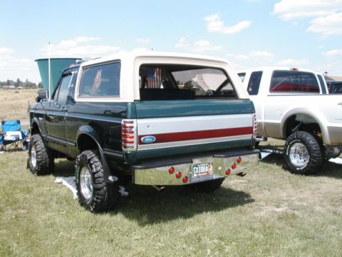 1994 Ford Bronco - Rear view of a lifted 1994 Ford Bronco with a two-tone paint scheme and custom chrome bumper.